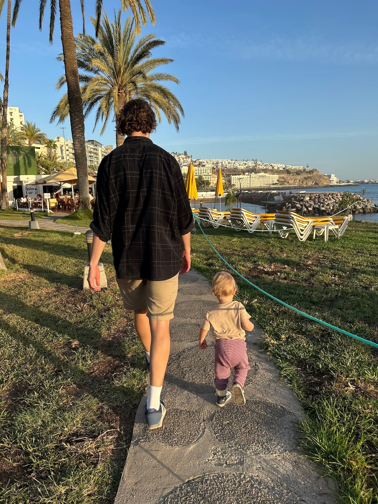 Andreas går med datteren sin langs en strandpromenade på Gran Canaria